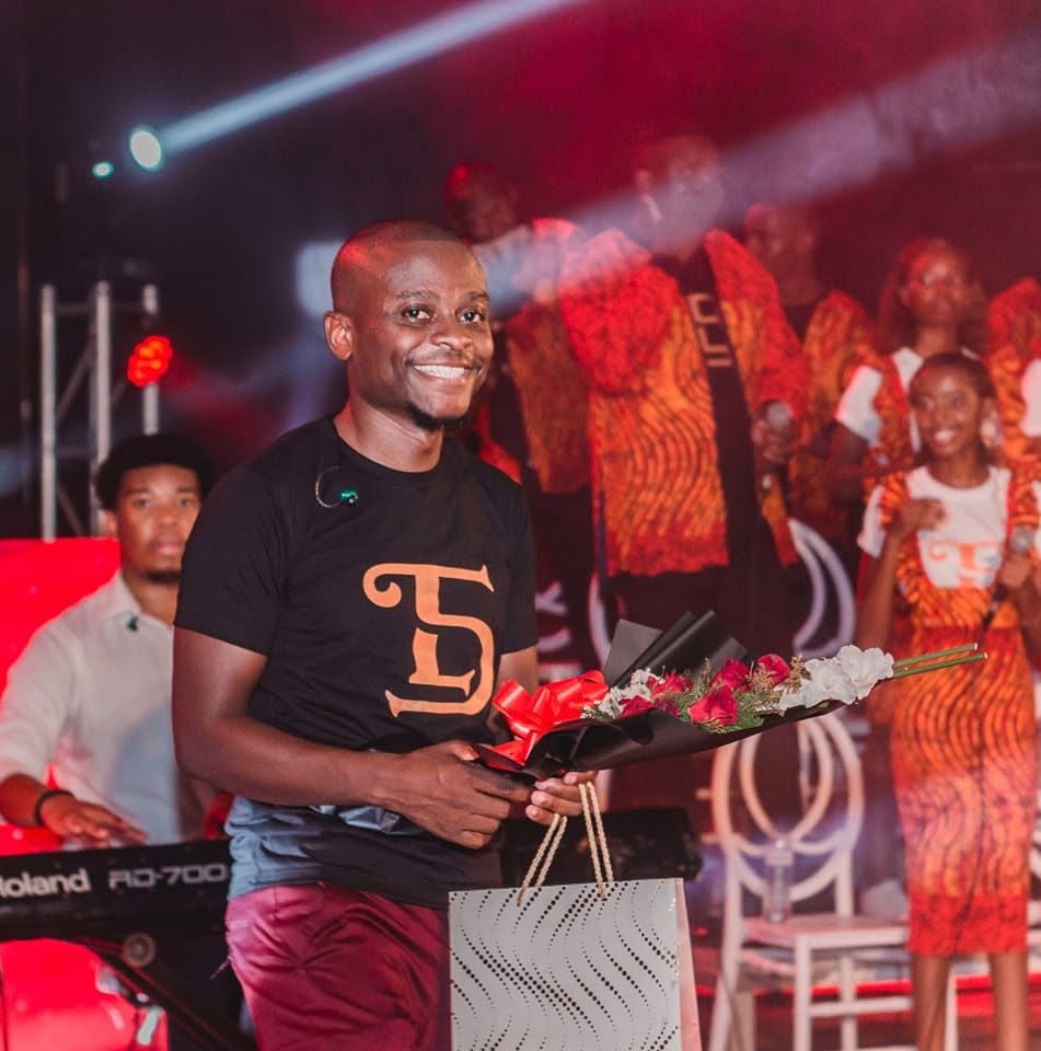 Tomás Mathe a sorrir num palco, com um ramo de flores na mão